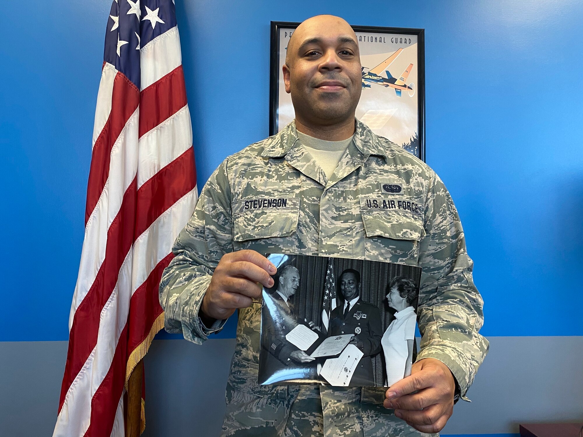 Man standing in air force uniform holding a picture frame.
