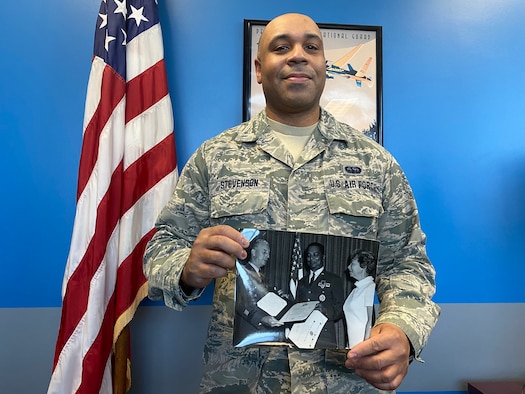 Man standing in air force uniform holding a picture frame.