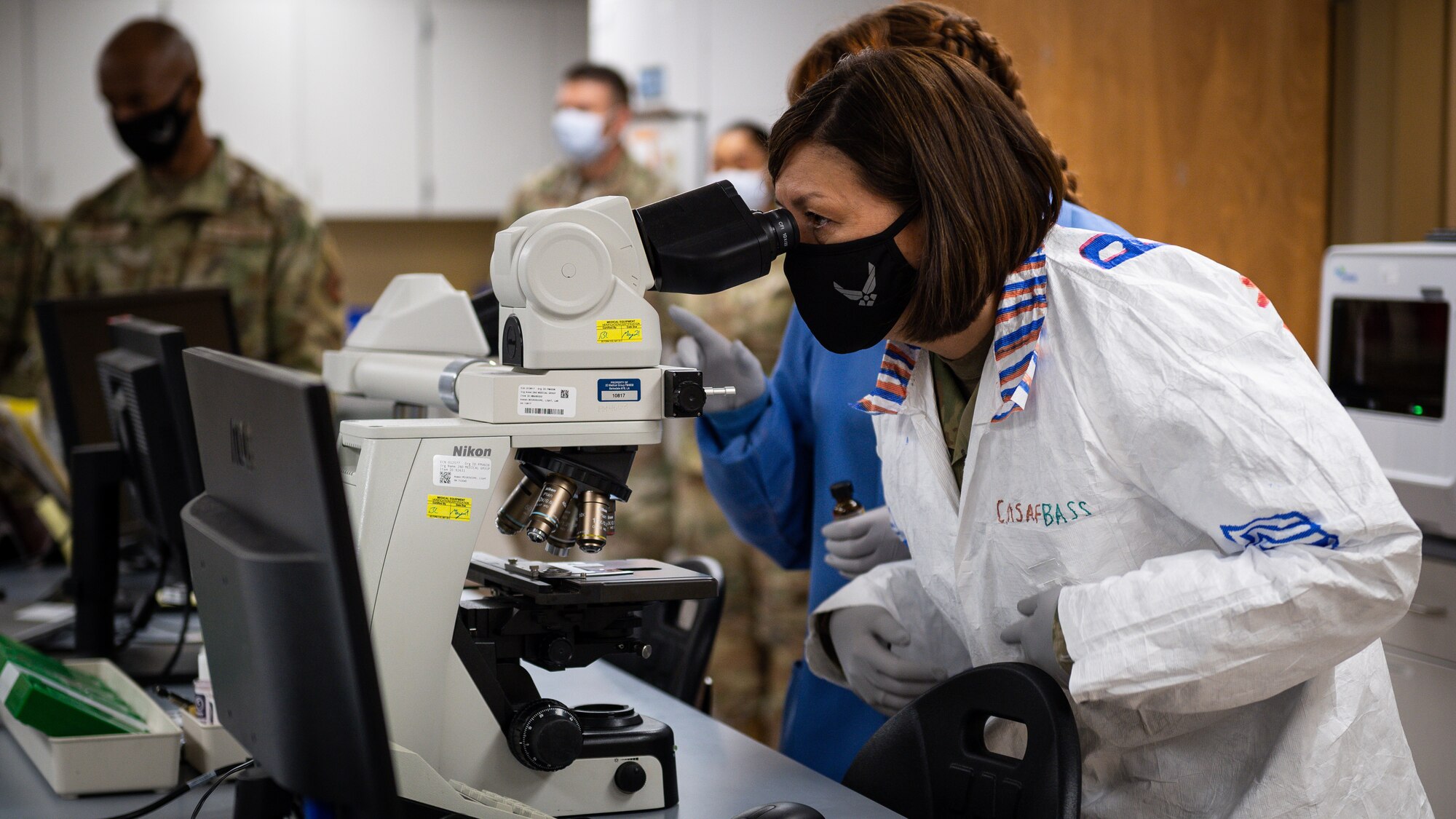 Chief Master Sergeant of the Air Force JoAnne S. Bass, looks through a microscope during a tour of Barksdale Air Force Base, Louisiana, April 21, 2021.