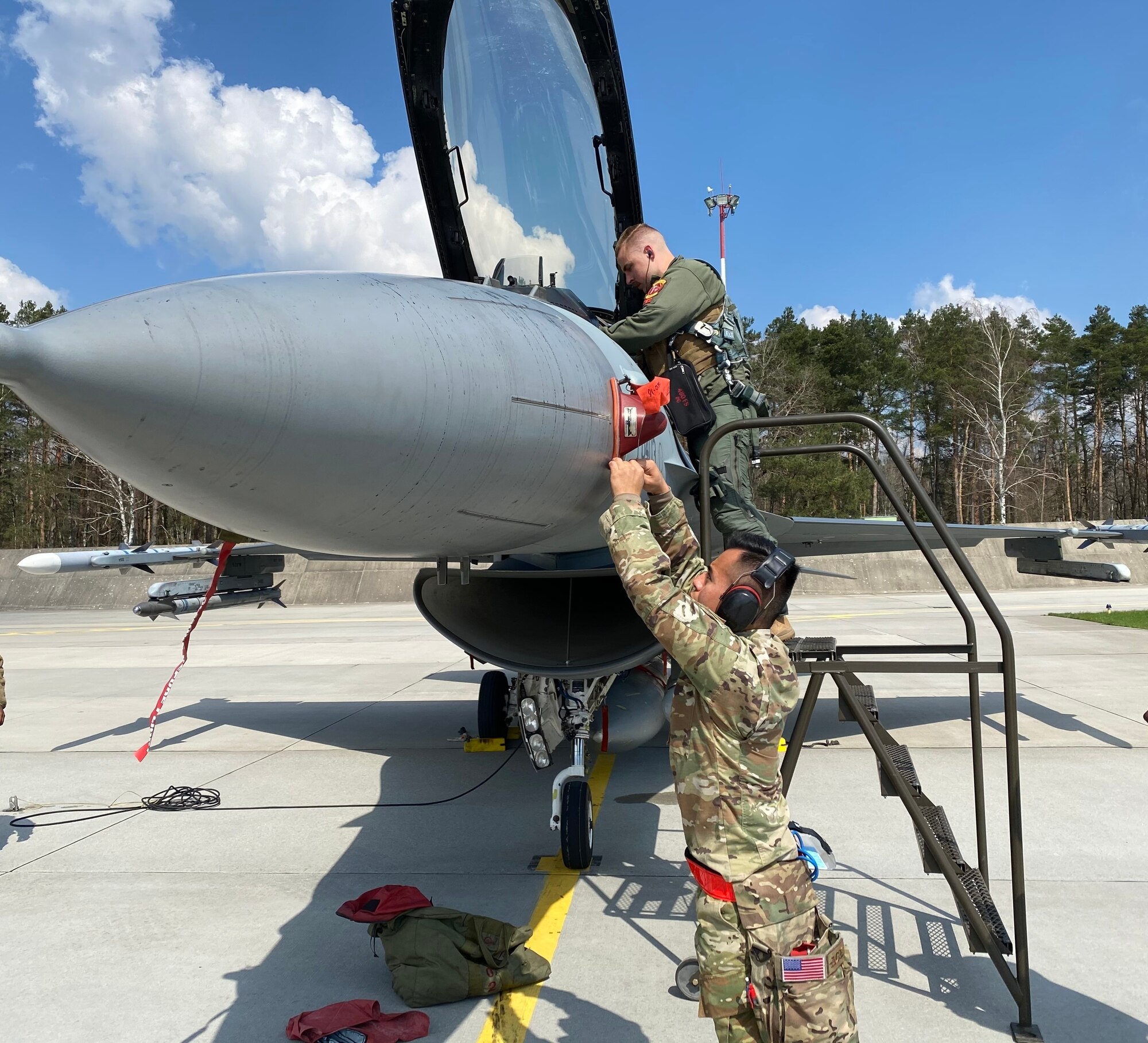 U.S. Air Force 1st Lt. Bjorn Nielsen, 480th Fighter Squadron pilot, and U.S. Air Force Airman First Class Christopher Flores, 52nd Aircraft Maintenance Weapons Load Crew member, help recover a U.S. Air Force F-16 Fighting Falcon after arrival, during an Agile Combat Employment exercise at Łask Air Base, Poland, April 19, 2021.