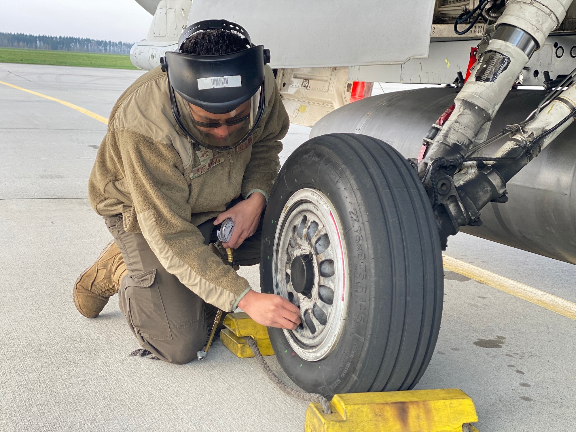 U.S. Air Force Tech. Sgt. Shaun Fielding, 52nd Aircraft Maintenance Squadron Weapons Load Crew chief, checks the tire pressure on a U.S. Air Force F-16 Fighting Falcon at an Agile Combat Employment exercise at Łask Air Base, Poland, April 21, 2021.