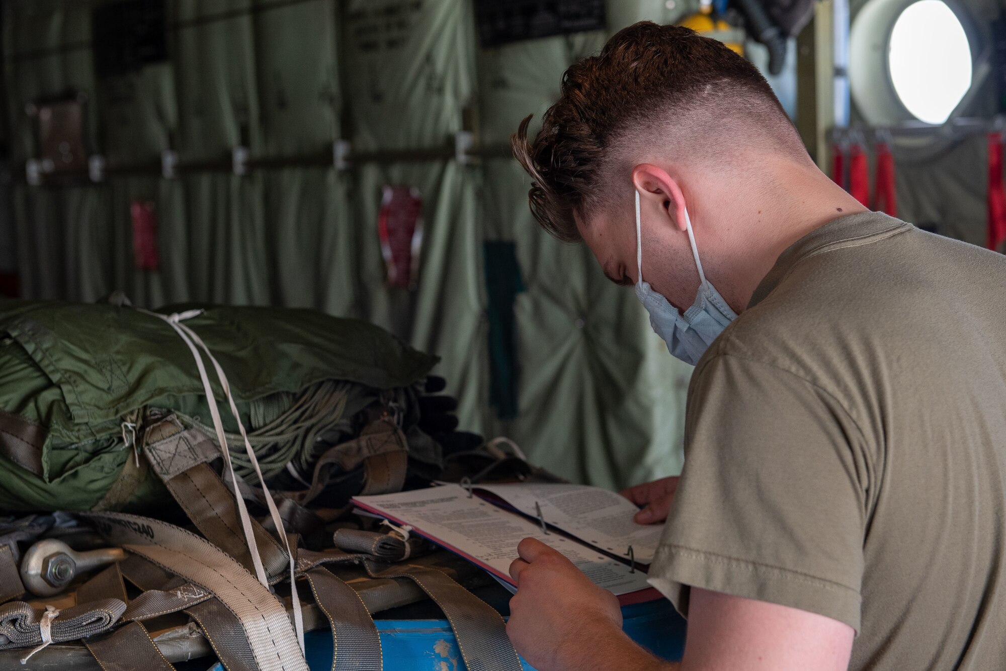 An Airman references instructions for securing a pallet in an aircraft.