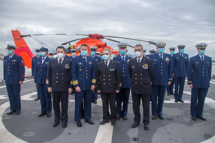 Members from the Italian Coast Guard and USCGC Hamilton (WMSL 753) pose for a photo in front of a U.S. Coast Guard MH-65 Dolphin helicopter aboard Hamilton, April 23, 2021.
