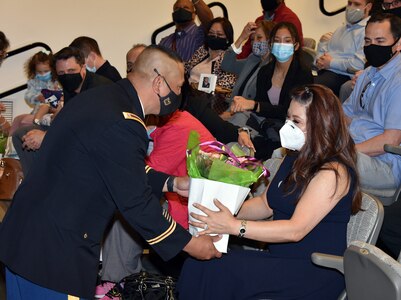 Chief Warrant Officer 5 Jesus C. Tulud presents a gift to his wife, Chae, during his retirement ceremony April 15 at Fort Detrick, Maryland. Tulud most recently served as command chief warrant officer at U.S. Army Medical Logistics Command and director of AMLC’s Medical Maintenance Policies and Analysis directorate. (Photo Credit: C.J. Lovelace)