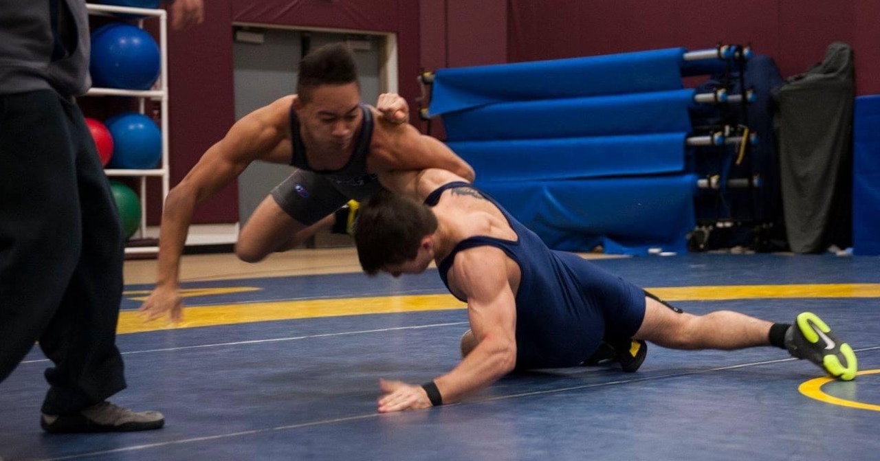 Two wrestlers compete on a mat.