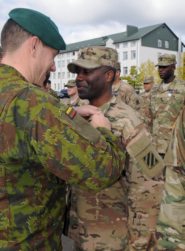 A foreign military service member pins a medal on a U.S. soldier.