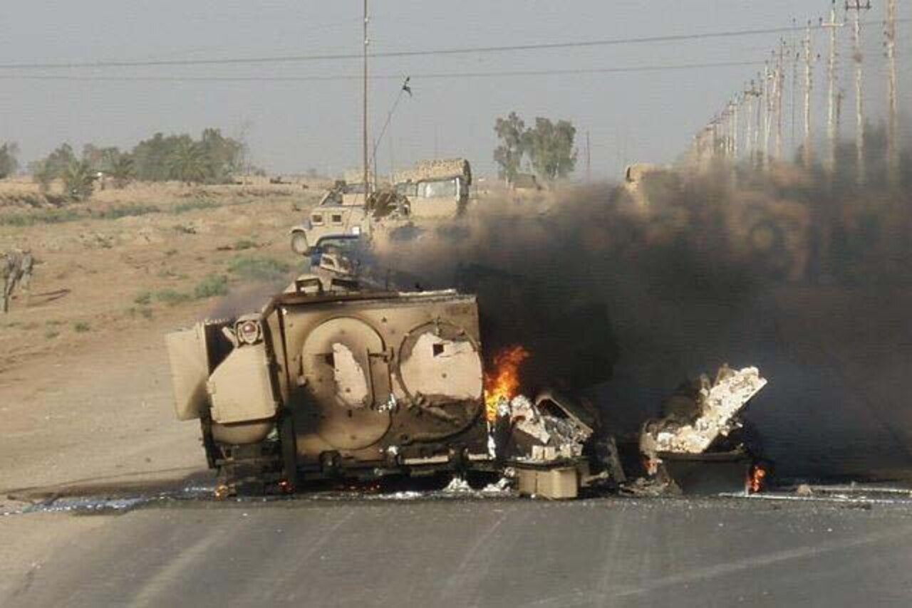 A military vehicle burns on a street in Iraq.