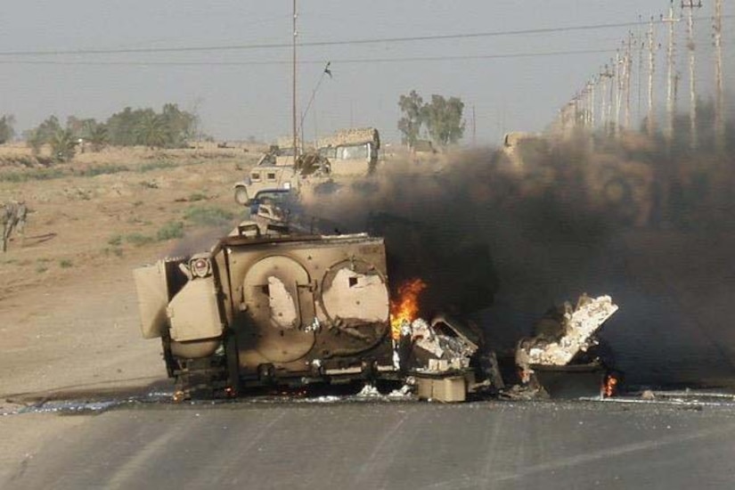 A military vehicle burns on a street in Iraq.