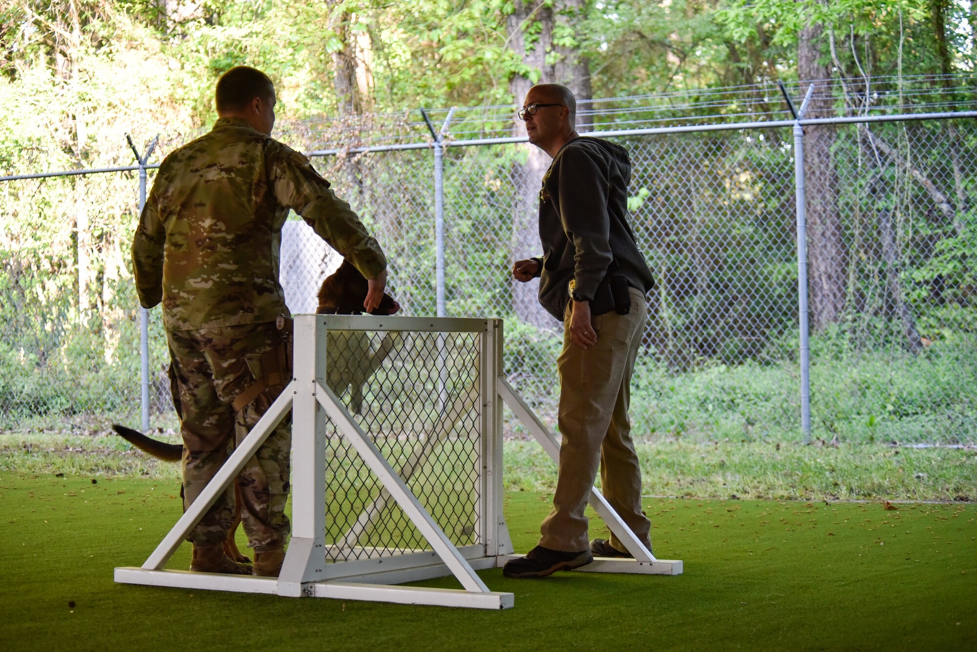 Tech. Sgt. Dakota Willis, left, 4th Security Forces Squadron military working dog section noncommissioned officer in charge, works with John Taylor, right, North Carolina State Bureau of Investigation special agent, to train Nick, NCSBI explosives detection canine, to jump a fence at Seymour Johnson Air Force Base, North Carolina, April 20, 2021. Dog handlers and their dogs from the NCSBI and other agencies joined up with Team Seymour MWD handlers in a joint training day. (U.S. Air Force photo by Staff Sgt. Kenneth Boyton)