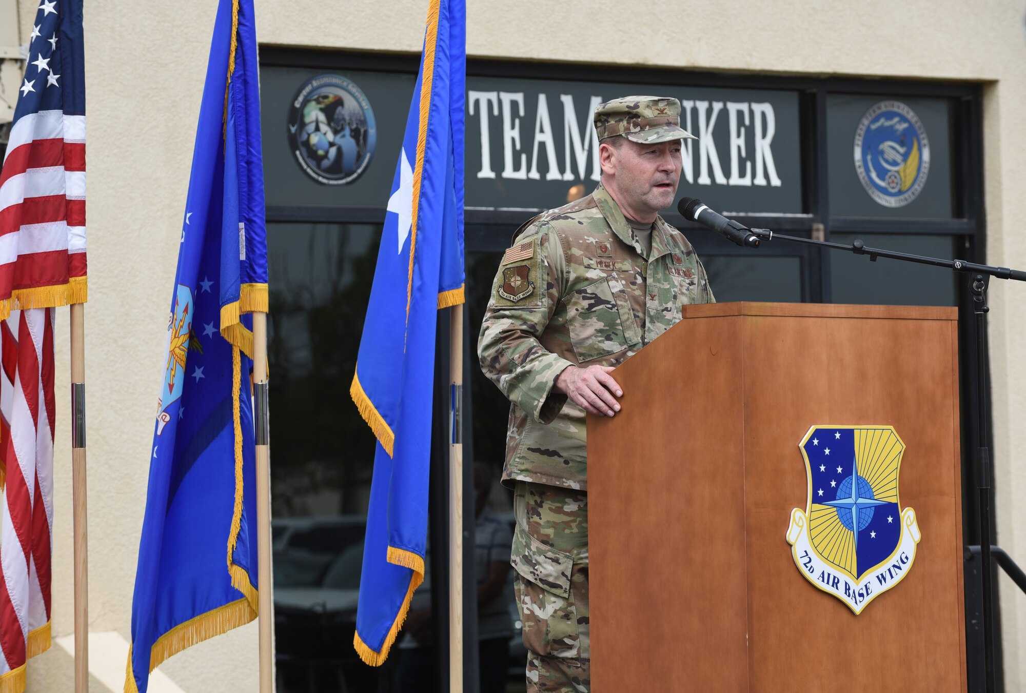Man speaking at podium with flags in the background