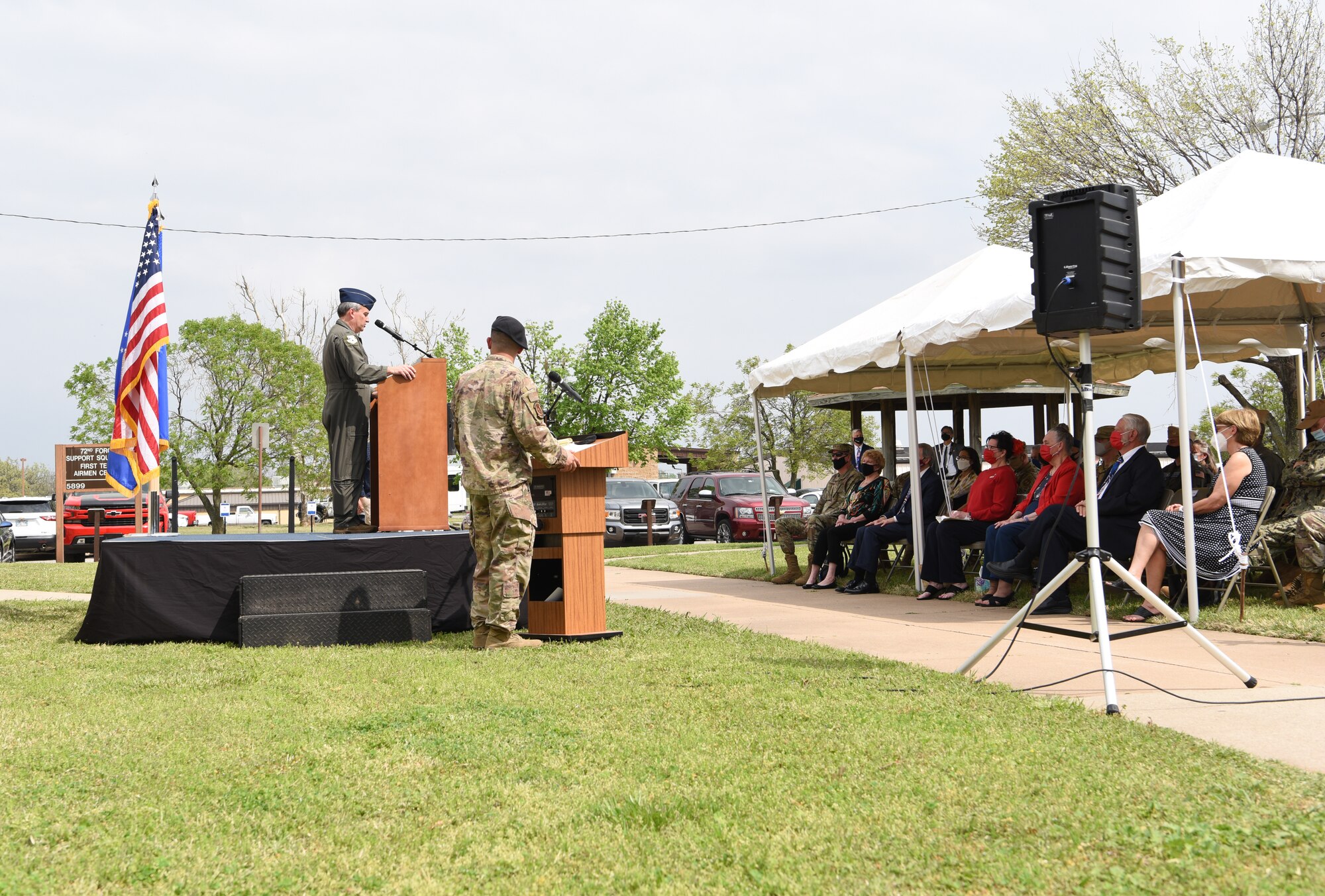 Man standing at podium with crowd sitting listening.