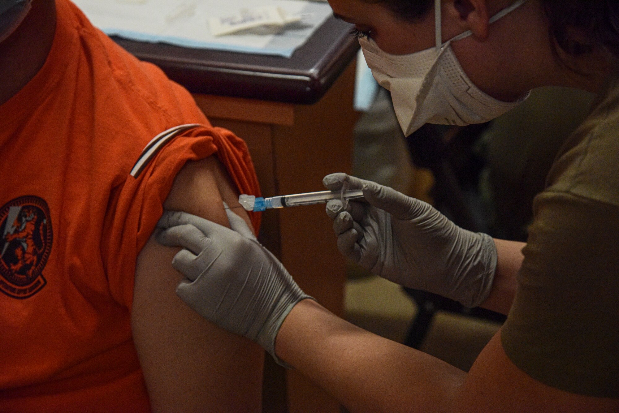 A photo of a Medical worker administering a vaccine to an Airman.