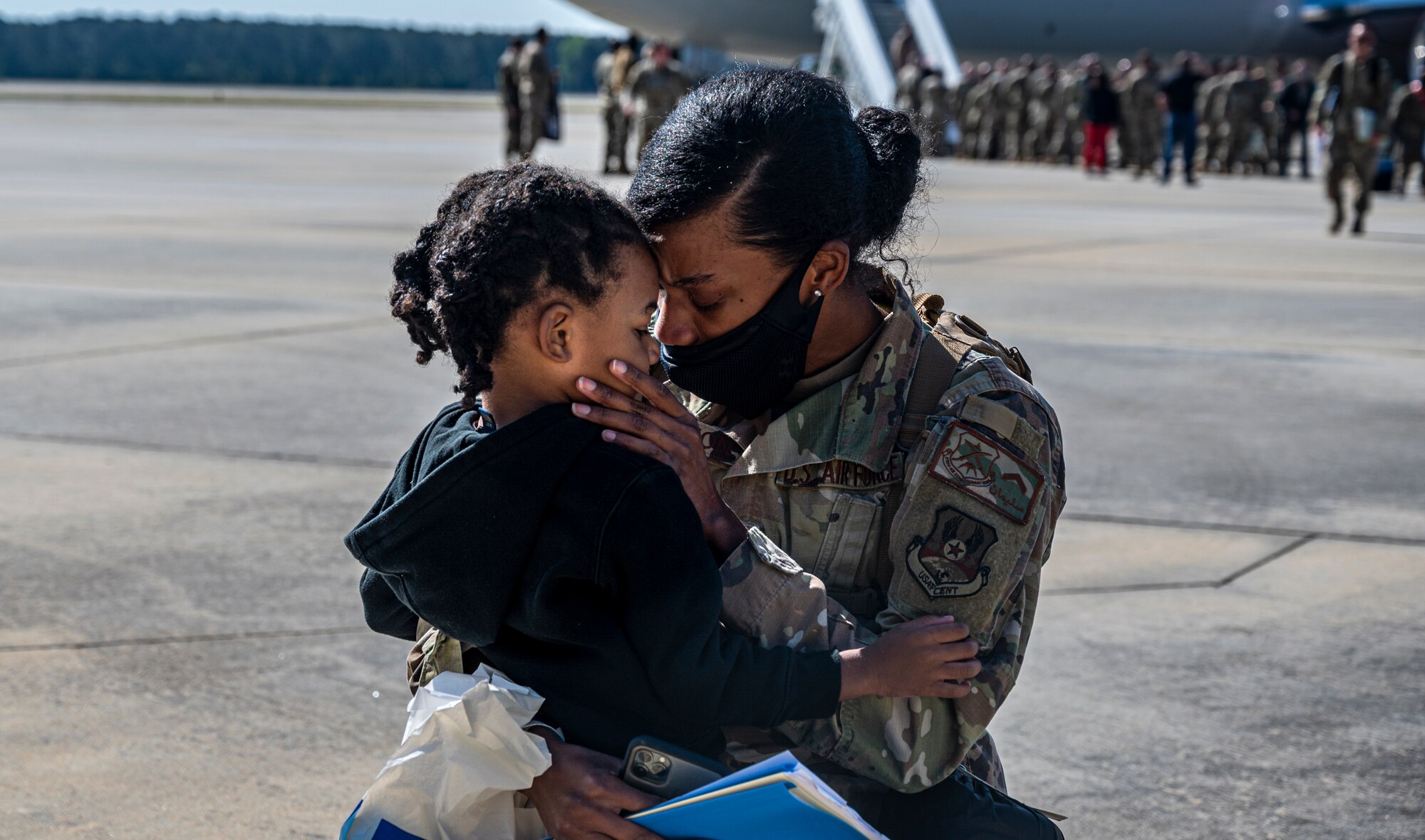 A photo of an Airman embracing a child on the flightline.