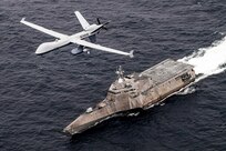 An unmanned aircraft flies over a Navy ship traveling in the sea.