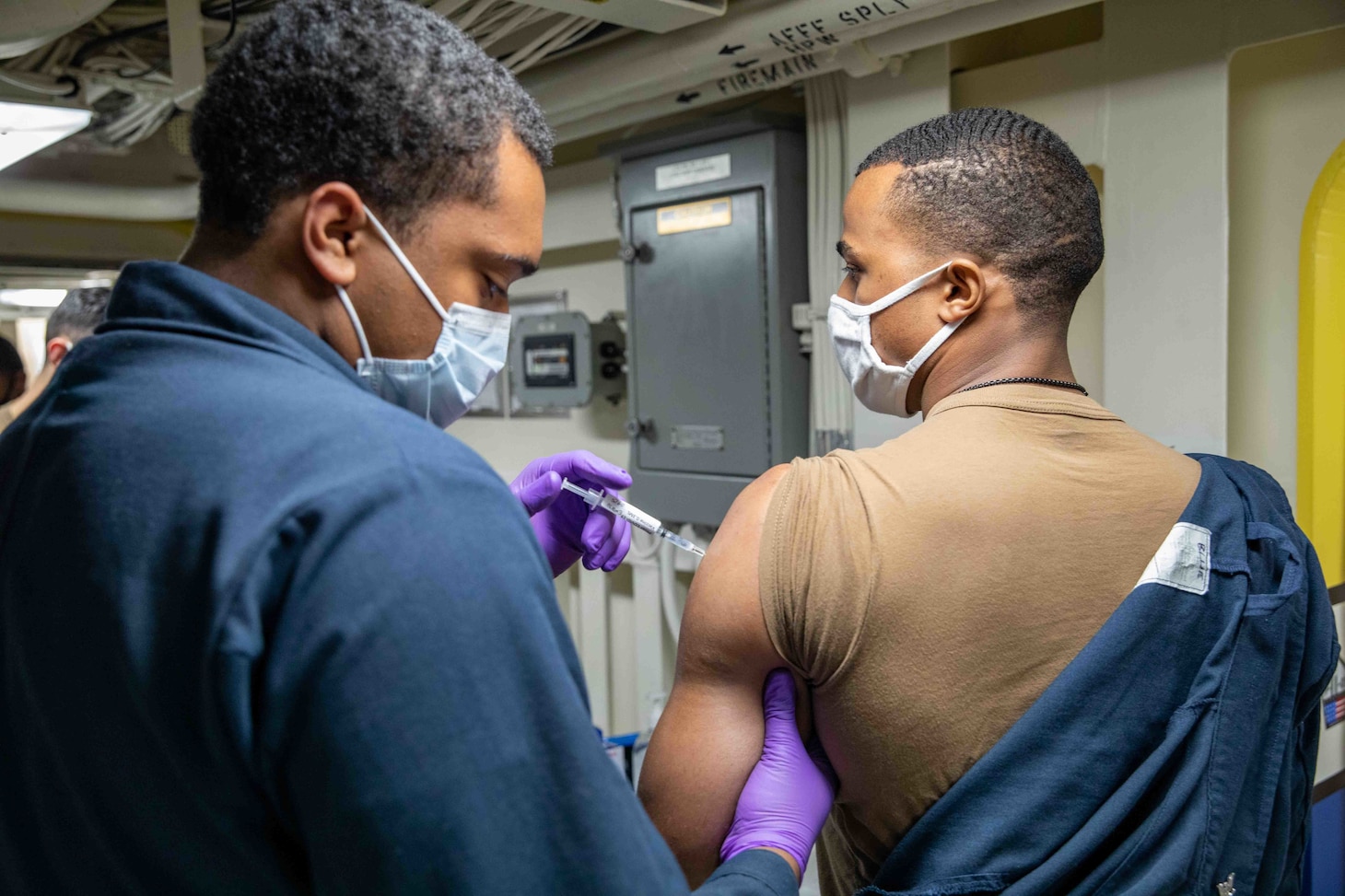 Hospitalman Marcus Wooten, assigned to the San Antonio-class amphibious transport dock ship USS Arlington (LPD 24) administers a COVID-19 vaccine to Information System Technician 3rd Class Caleb Blue, April 23.