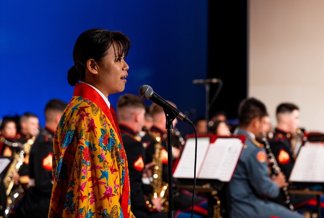 Japan Ground Self-Defense Force (JGSDF) Sgt. Mio Sakuma, a french horn player with the JGSDF 15th Brigade band sings “Bashofu Bossa Nova,” an Okinawan folk song during the spring concert in Tedako Hall in Urasoe, Okinawa, Japan, April 16, 2021. The bands' harmonious performance was a display of the III Marine Expeditionary Force and 15th Brigade bands' alliance and unity within the musical arts. The annual concert was performed virtually and the recording will debut on social media platforms within the coming weeks. Sakuma is a native of Fukuoka. (U.S. Marine Corps photo by Cpl. Terry Wong)