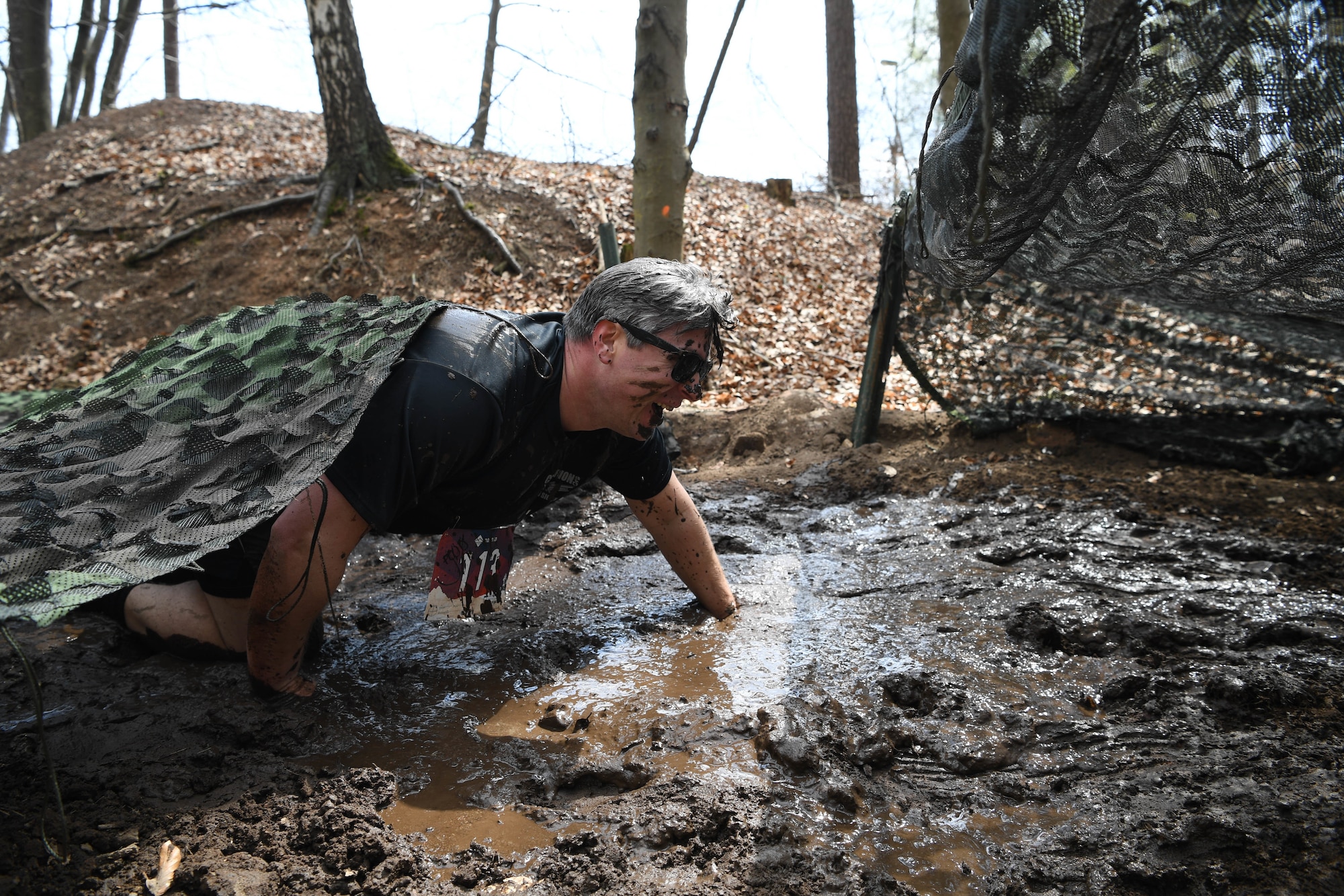 Airman crawls through the mud