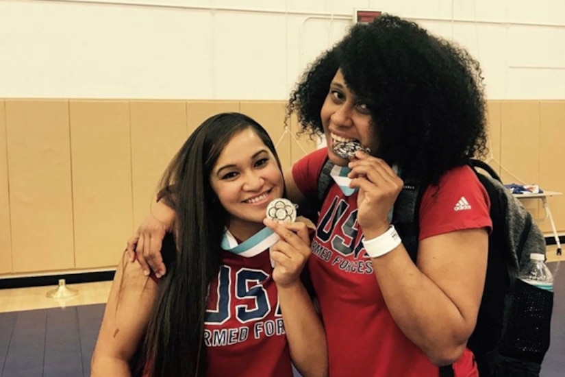 Two athletes show off their medals as they pose for a photo.