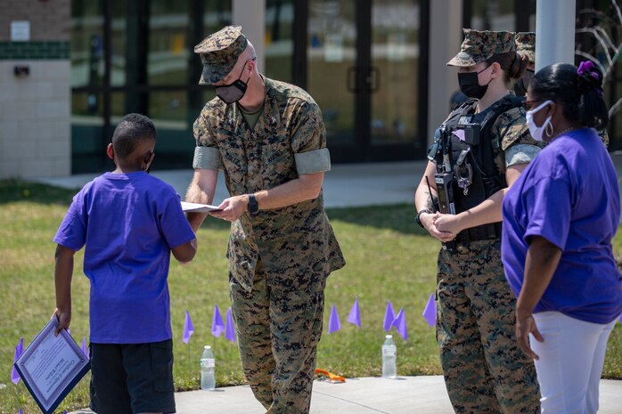 U.S. Marine Corps Col. Curtis V. Ebitz, center, the commanding officer of Marine Corps Air Station New River, hands out an award during a ceremony at Delalio Elementary School on MCAS New River, North Carolina, April 8, 2021. April is the month of the military child, highlighting the important role military children play in the armed forces community. (U.S. Marine Corps photo by Lance Cpl. Isaiah Gomez)