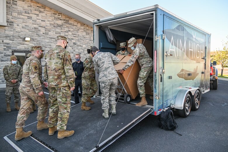 Airmen unload a box from a trailer.