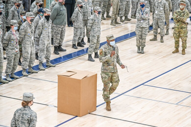 Senior Airman Spain addresses students standing in formation inside a gymnasium.