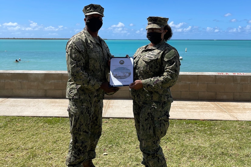 A woman and man, both in uniform, hold a certificate.