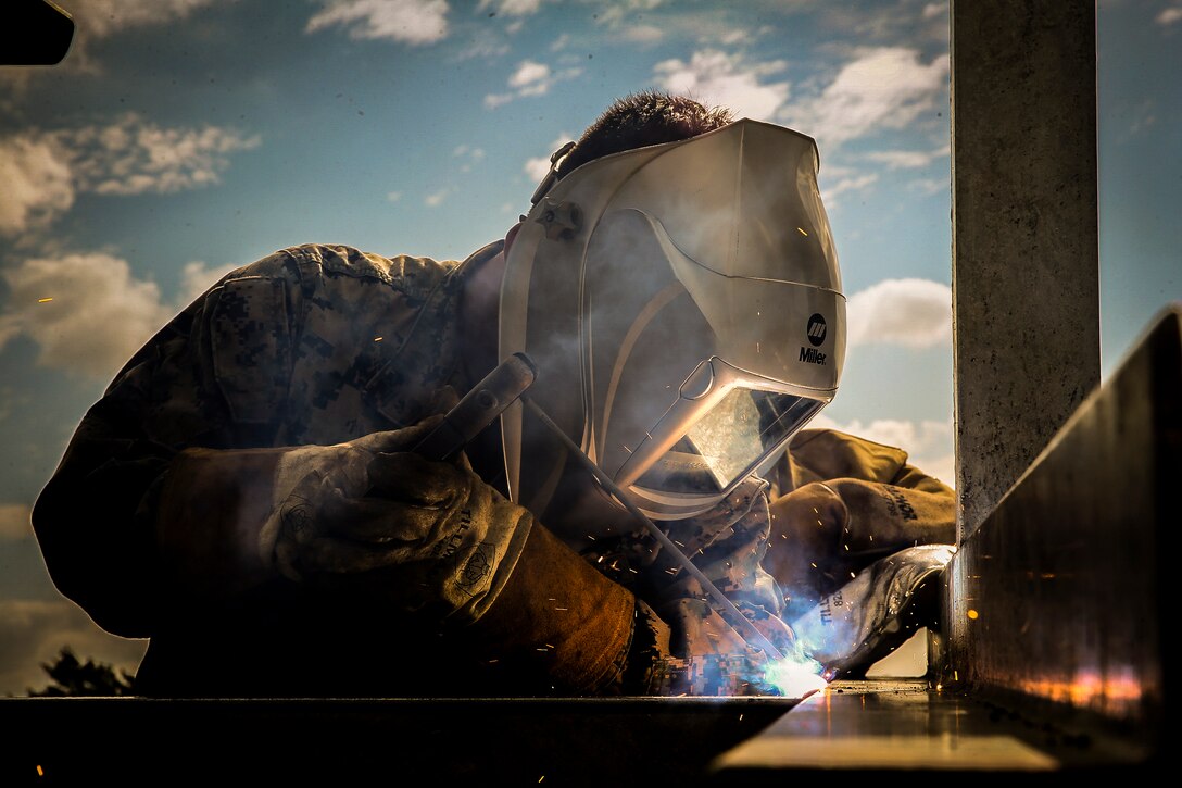 A Marine welds metals as sparks fly.