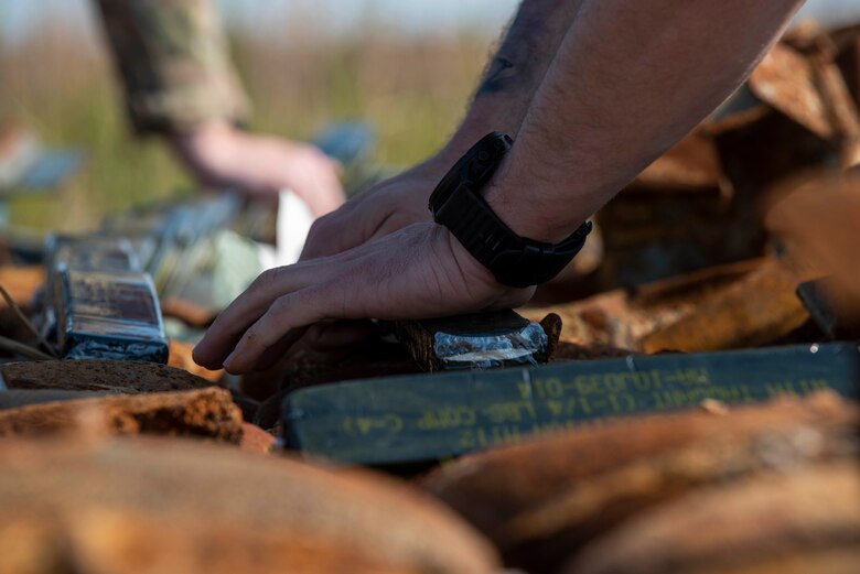 Airman 1st Class Joseph Plato 4th Civil Engineer Squadron explosive ordinance disposal technician places C-4 explosives on bomb dummy units (BDU) for a controlled explosion at Dare County Bomb Range, North Carolina, April 19, 2021.