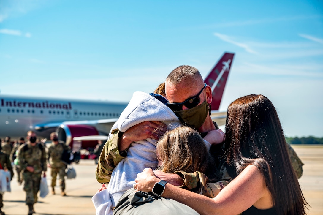 A family hugs near an aircraft.