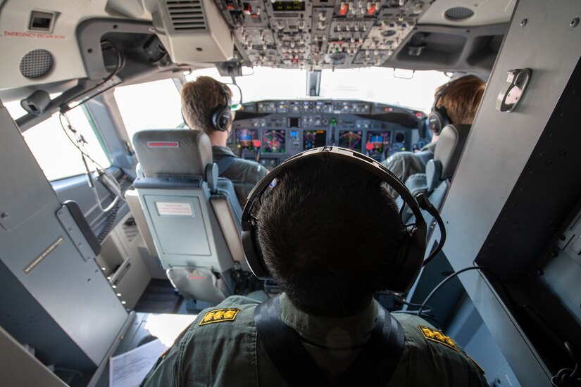 A three-person crew operates in an aircraft flight deck.