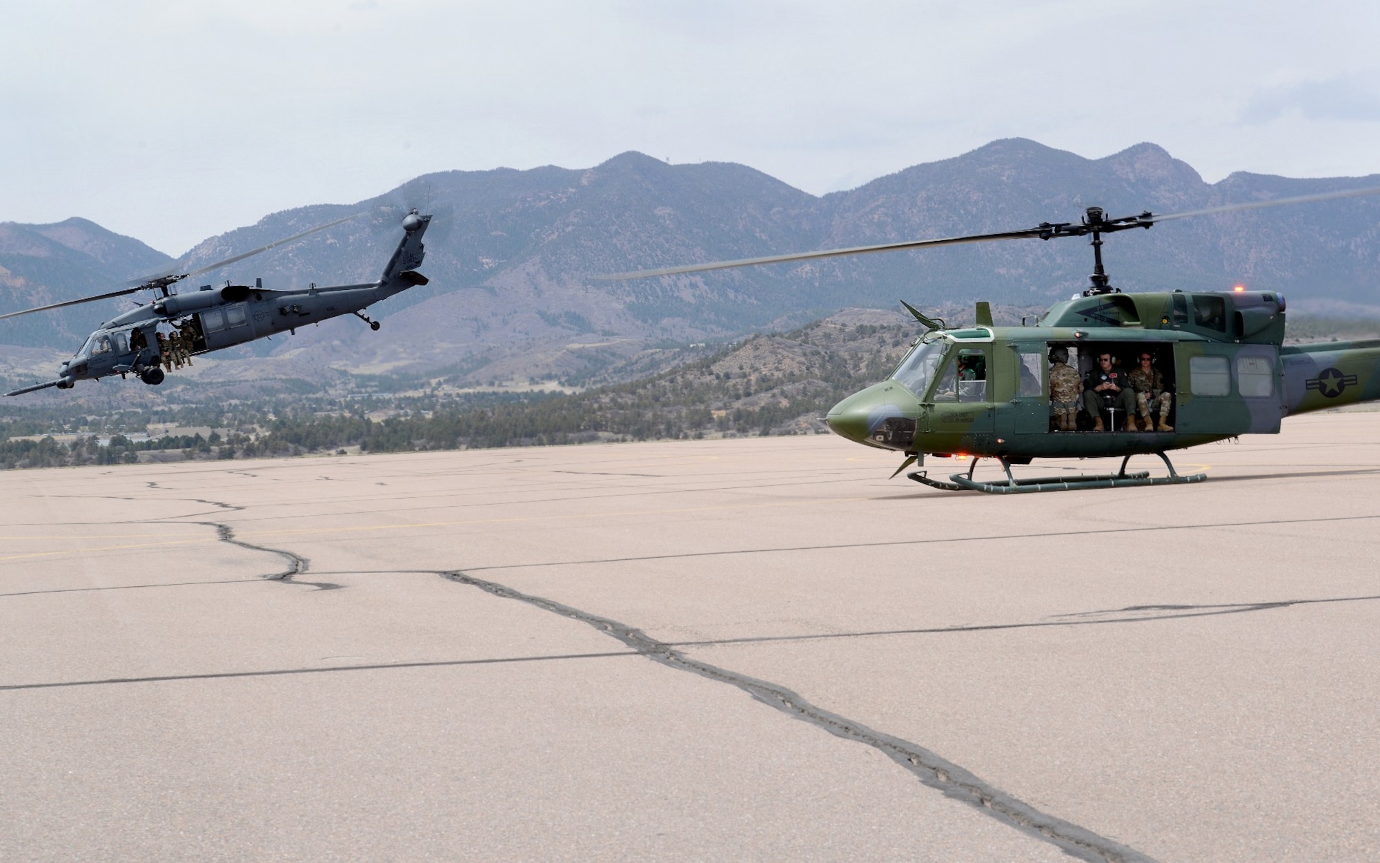 An HH 60-G helicopter lifts off from the airfield at the U.S. Air Force Academy while a UH-1 N gets ready to follow during