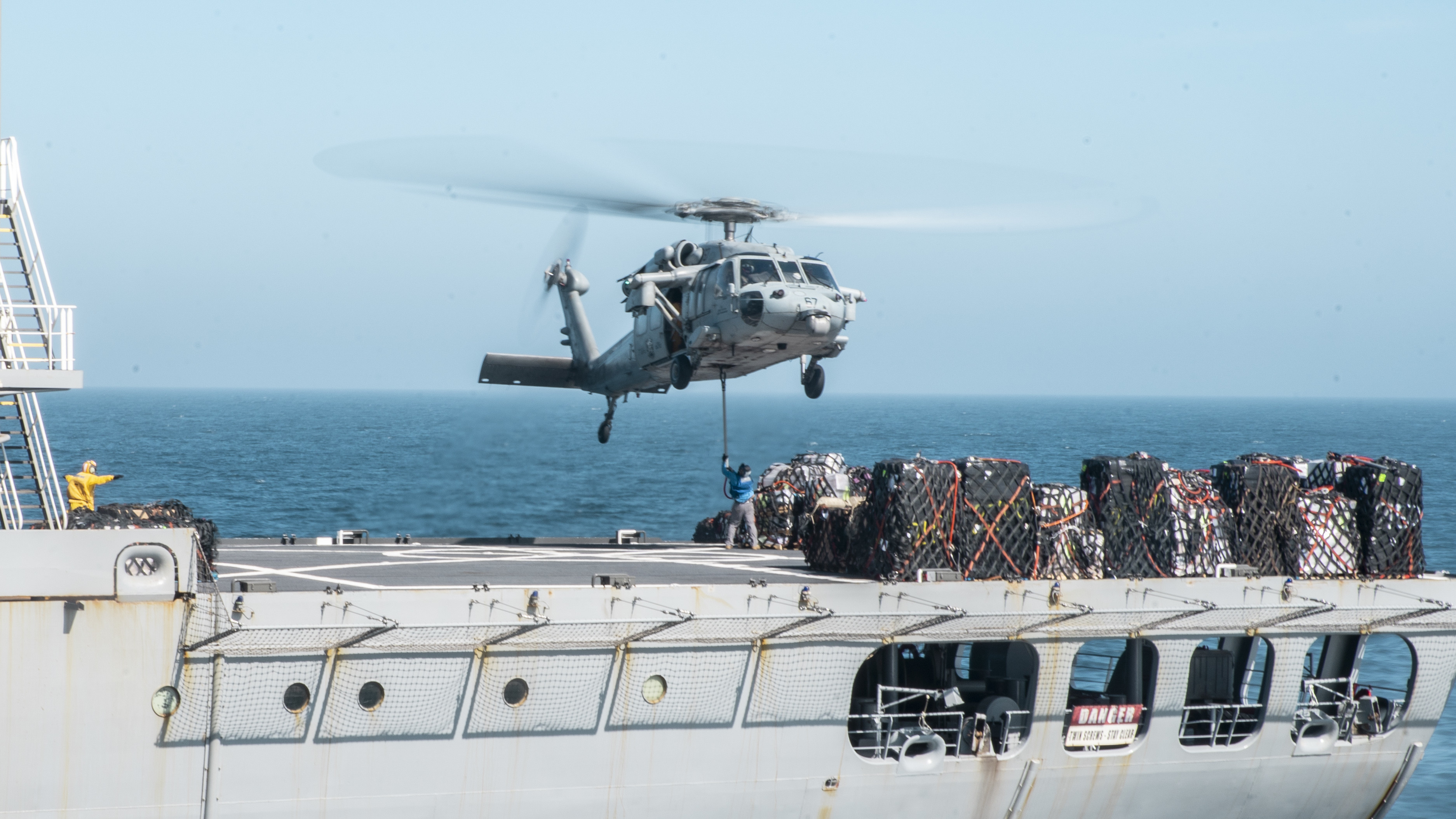 A U.S. Navy MH-60S Sea Hawk assigned to Helicopter Sea Combat Squadron (HSC) 21 retrieves cargo from the fleet replenishment oiler USNS Henry J. Kaiser (T-AO 187) during a vertical replenishment-at-sea.