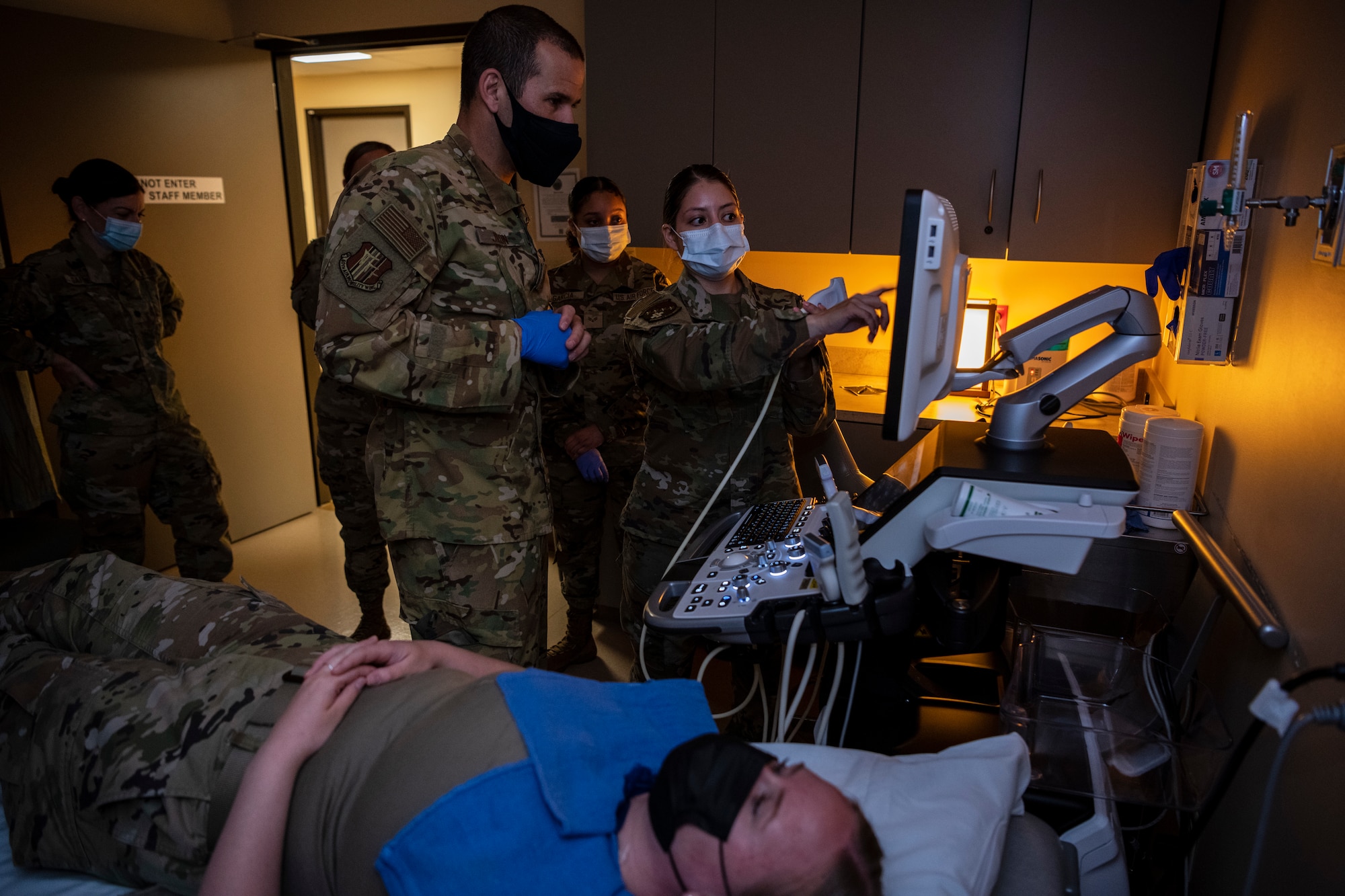 Airmen teach much higher ranking Airmen how to perform an ultrasound to a patient.