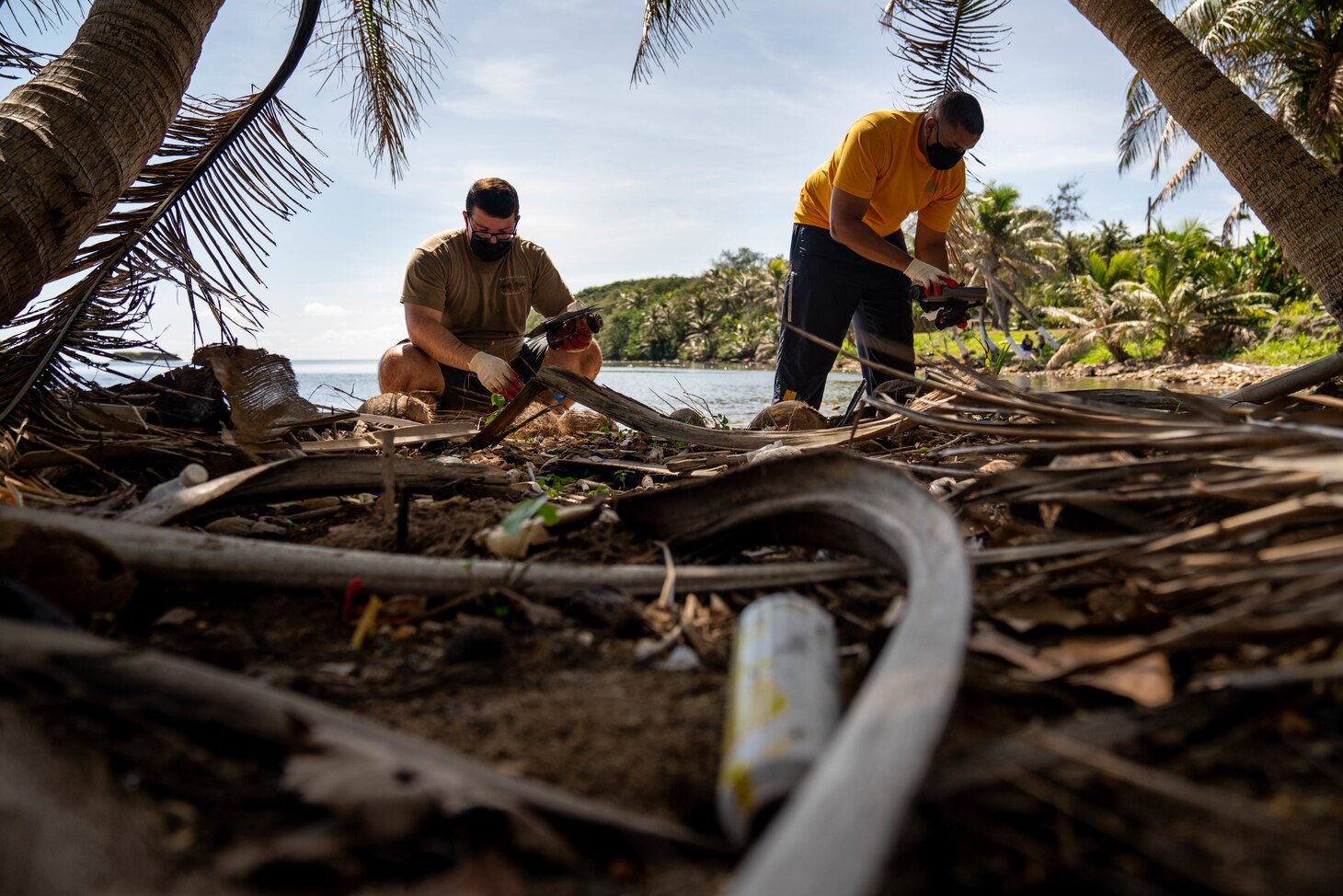 INALÅHAN, Guam (April 23, 2021) Lt. Cmdr. Andrew Regalado (right), from New York City, and Fire Control Technician 2nd Class Patrick Trevino, from Versailles, Kentucky, both assigned to Commander, Submarine Squadron 15, collect trash off the beach. CSS-15 and Naval Submarine Training Center Pacific, Detachment Guam, joined forces with their sister village, Inalåhan, during a volunteer event focused on environmental cleanliness to recognize Earth Day.