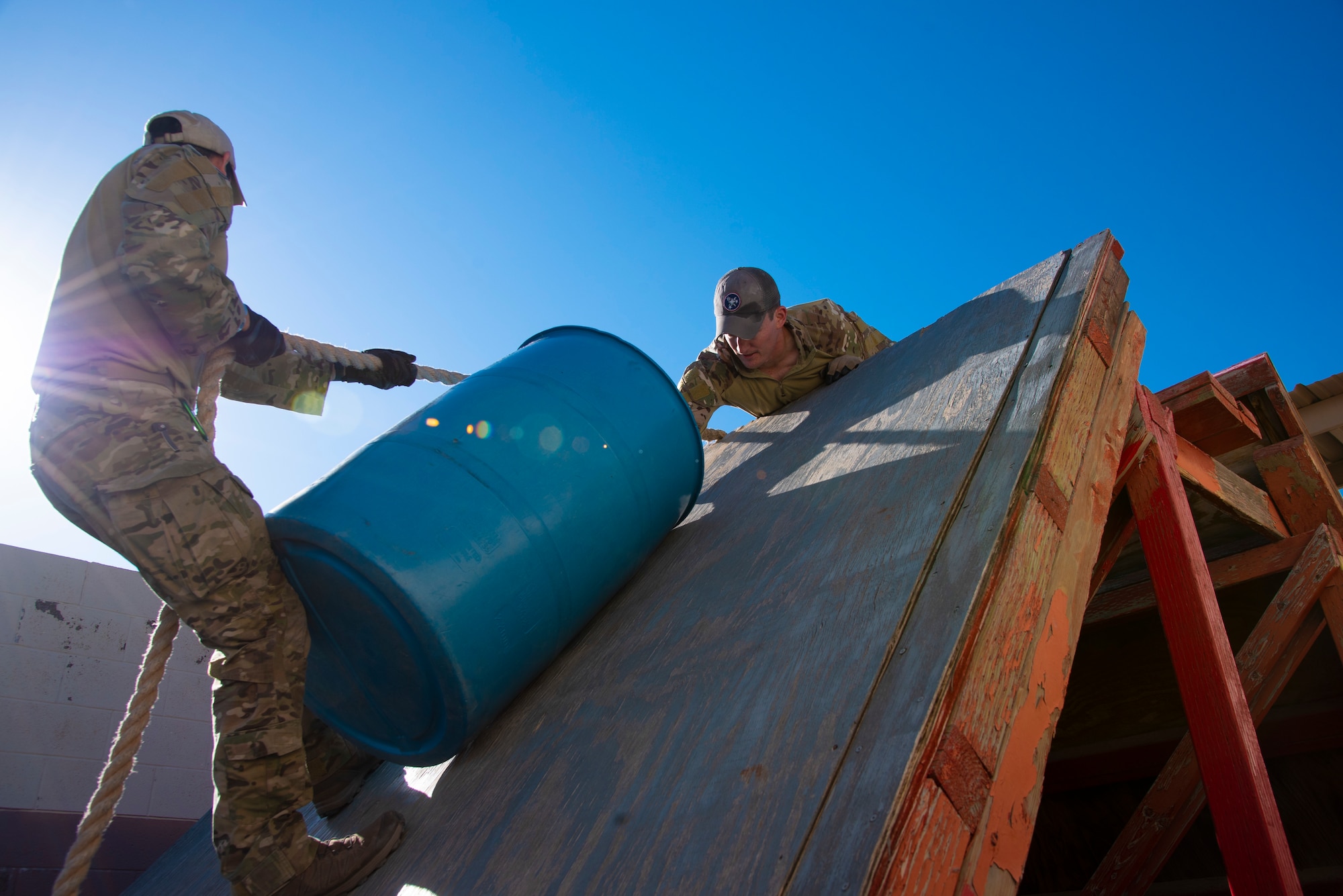 Two U.S. Air Force Tactical Air Control Party specialists carry a drum over an obstacle during the 2021 Wraith Challenge, April 20, 2021, on Fort Bliss, Texas. This was one of six obstacles in the leadership course. (U.S. Air Force photo by Airman 1st Class Jessica Sanchez)