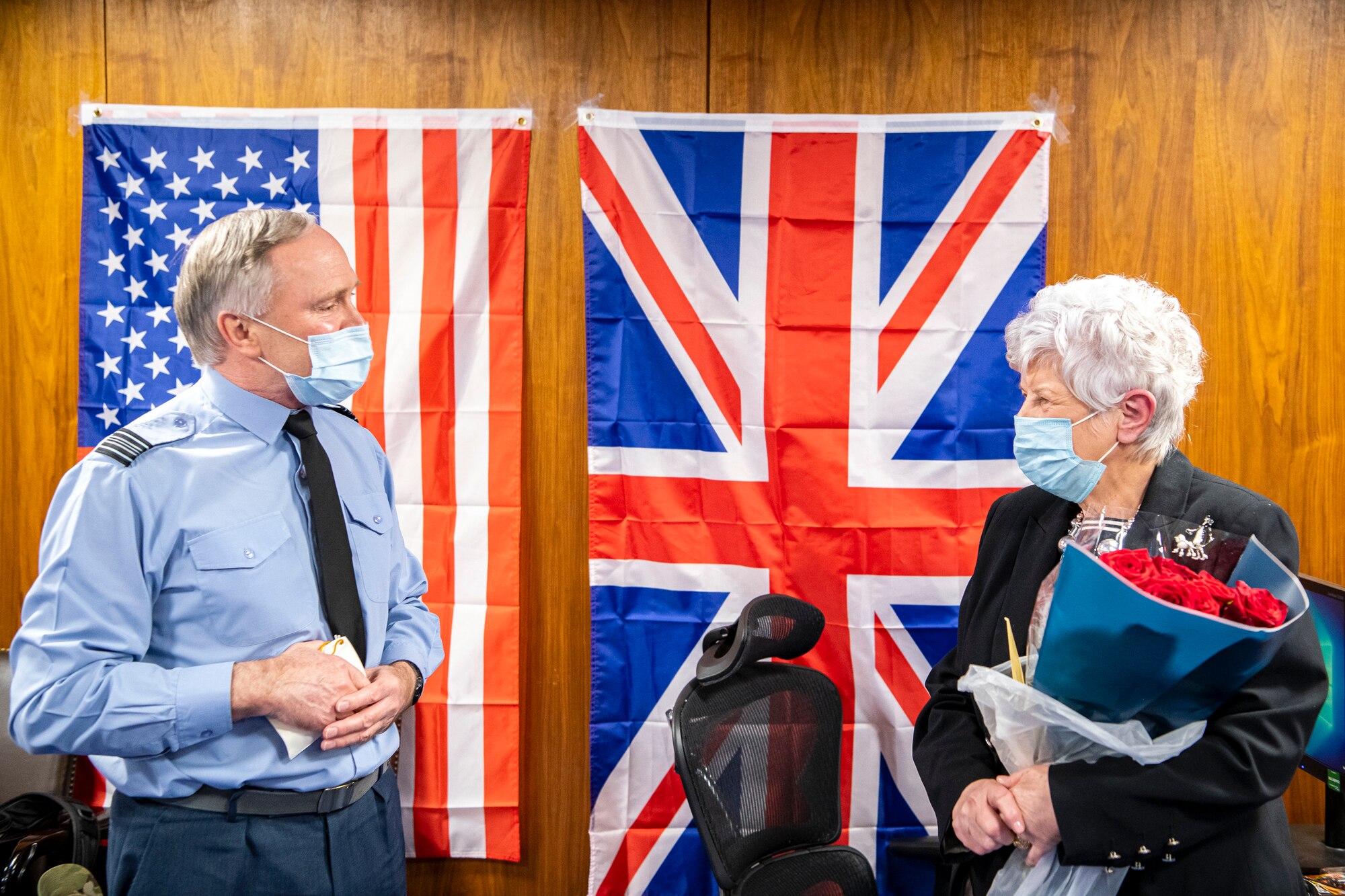 Squadron Leader Clive Wood, left, Royal Air Force Alconbury, RAF Molesworth and RAF Croughton commander, speaks with Valerie Lucas, 501st Combat Support Wing British liaison officer, during a celebration at RAF Alconbury, England, April 23, 2021. The 501 CSW/JA office celebrated Mrs. Lucas for her 60 years of service as the British liaison officer at RAF Alconbury. (U.S. Air Force photo by Senior Airman Eugene Oliver)