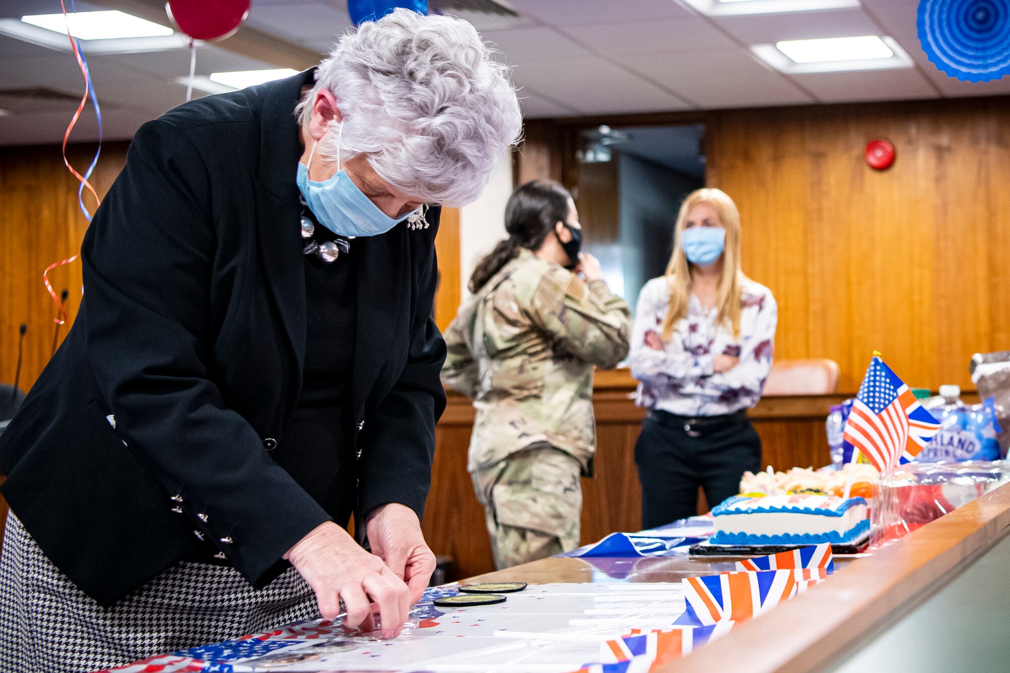 Valerie Lucas, Left, 501st Combat Support Wing, British liaison officer, picks up a coin during a celebration at RAF Alconbury, England, April 23, 2021. The 501 CSW/JA office celebrated Mrs. Lucas for her 60 years of service as the British liaison officer at RAF Alconbury. (U.S. Air Force photo by Senior Airman Eugene Oliver)