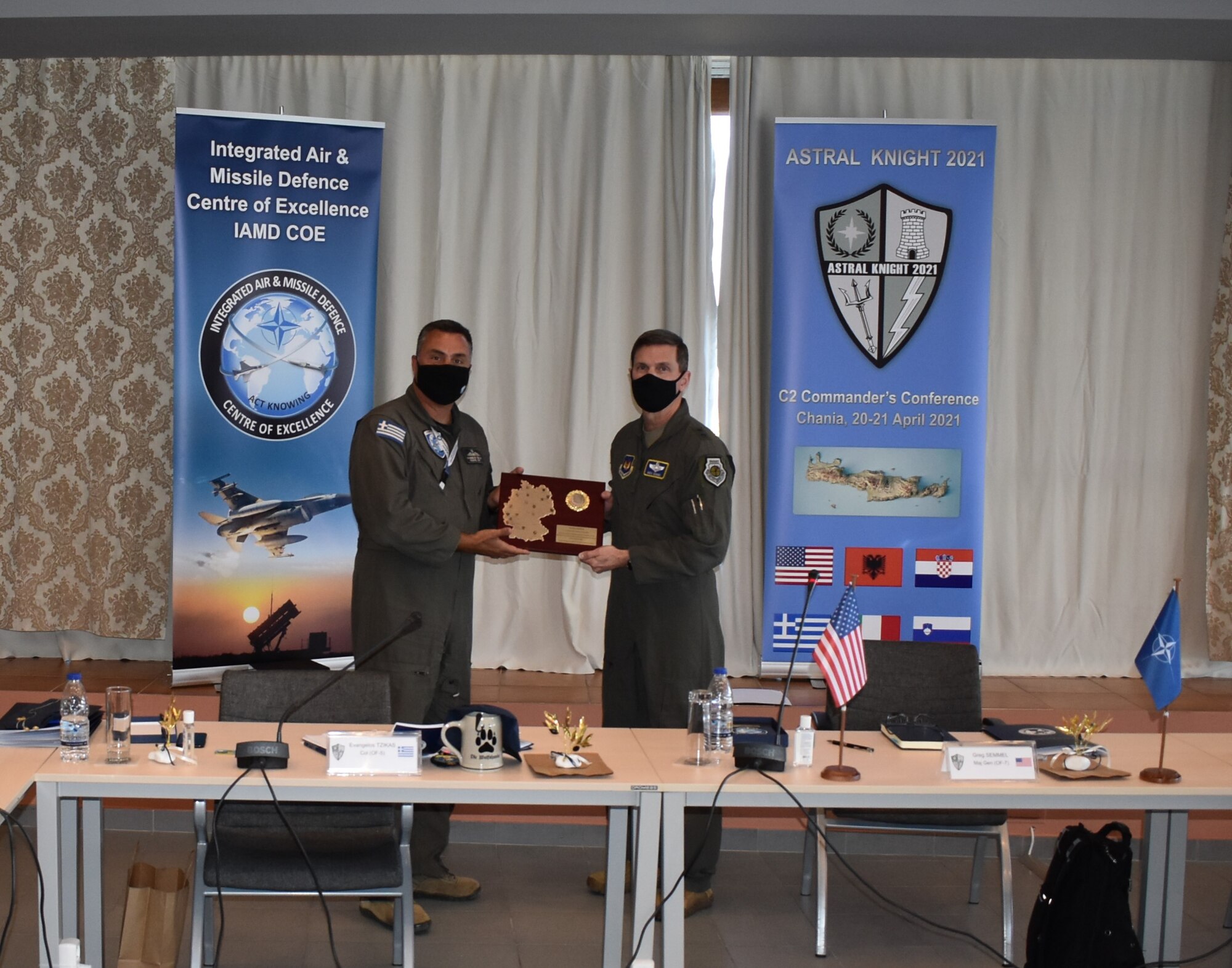 Hellenic Air Force Col. Evangelos Tzikas, Integrated Air and Missile Defense Center of Excellence director (left), receives an appreciation gift from U.S. Air Force Maj. Gen. Greg Semmel, Air National Guard assistant to COMUSAFE and ASTRAL KNIGHT 21 exercise director, on behalf of the participants of the Command and Control Commanders Conference in Chania, Crete on April 21, 2021. Commanders from six NATO nations attended the two-day conference to discuss IAMD coordination in the southern European region, in preparation for the upcoming USAFE-led exercise, AK21.