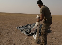 Rigger Spc. Andres Sanchez with the Fort Bragg, North Carolina, based 151st Quartermaster Company, deployed to the U.S. Central Command area of responsibility in support 1st Theater Sustainment Command, collects the rigging lines from one of the four parachutes that each successfully carried bundles within 75 meters of the target at the Camp Buehring, Kuwait, drop zone April 22, 2021 using the Joint Precision Air Delivery System, or JPADS. Sanchez said he appreciated the chance to participate in the real-world exercise.