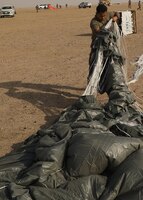 Rigger Spc. Andres Sanchez with the Fort Bragg, North Carolina, based 151st Quartermaster Company, deployed to the U.S. Central Command area of responsibility in support 1st Theater Sustainment Command, collects the rigging lines from one of the four parachutes that each successfully carried bundles within 75 meters of the target at the Camp Buehring, Kuwait, drop zone April 22, 2021 using the Joint Precision Air Delivery System, or JPADS. Sanchez said he appreciated the chance to participate in the real-world exercise.