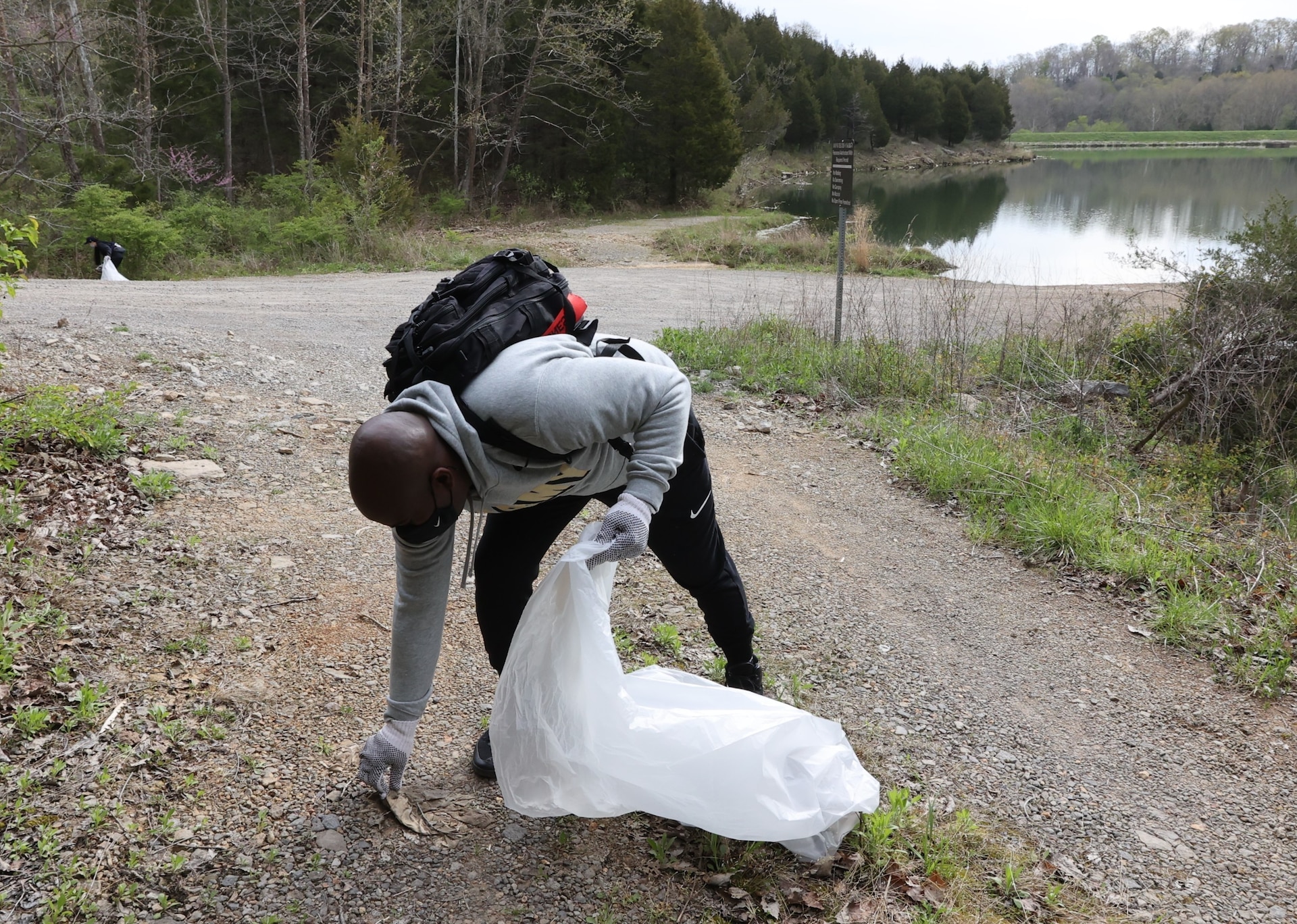 men and women gathering garbage and debris in the woods.