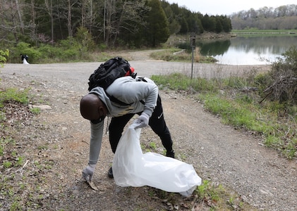 men and women gathering garbage and debris in the woods.