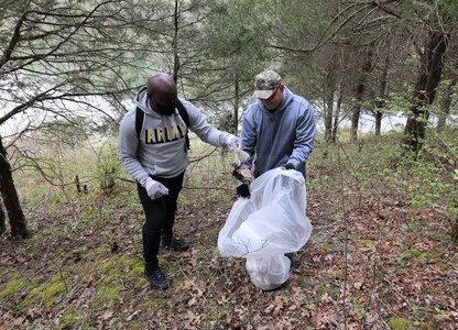 men and women gathering garbage and debris in the woods.
