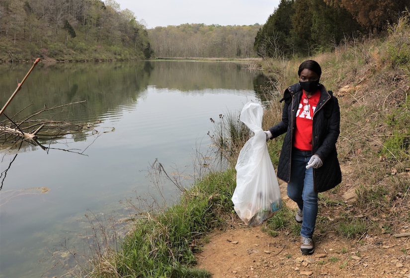 men and women gathering garbage and debris in the woods.