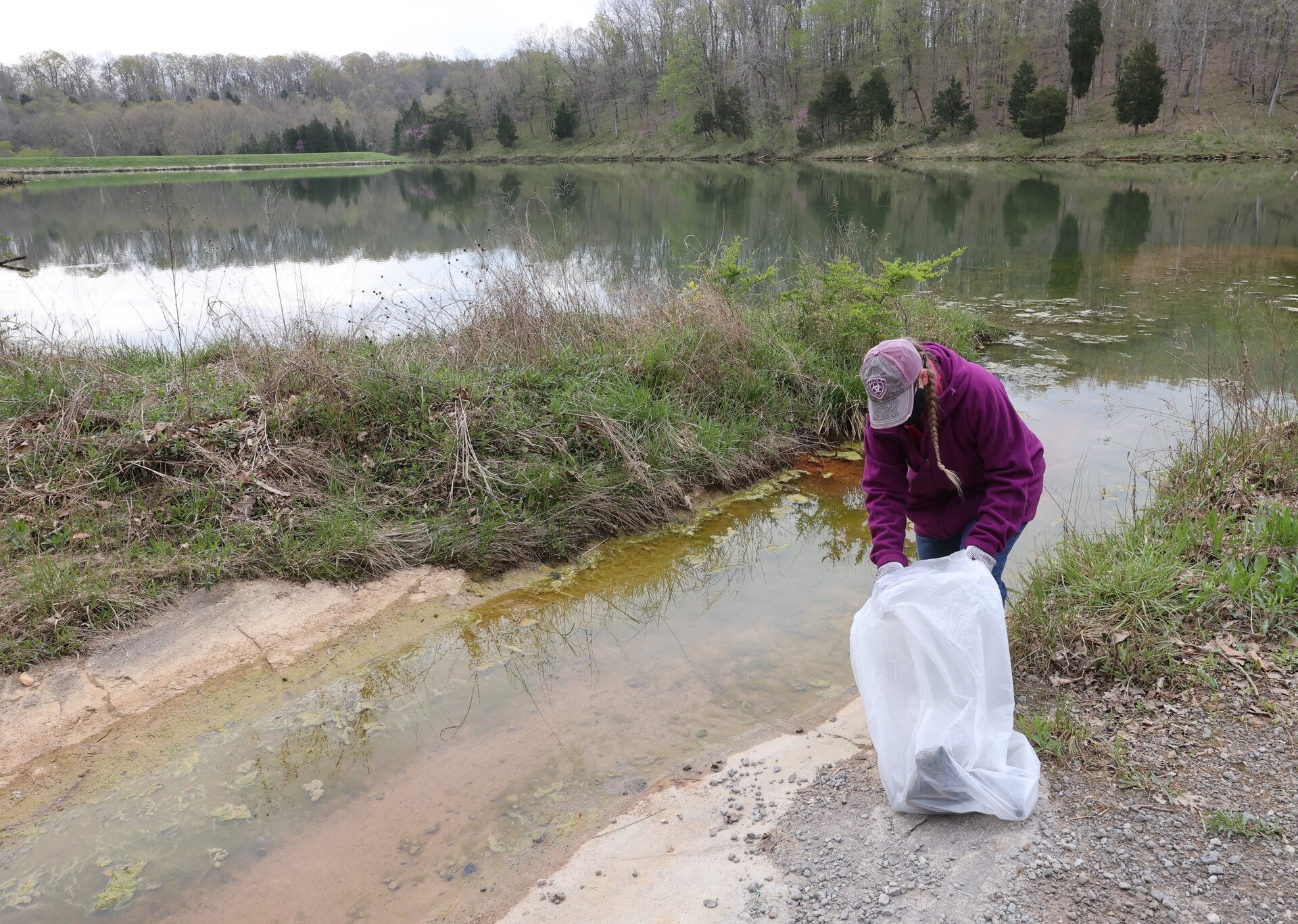 men and women gathering garbage and debris in the woods.
