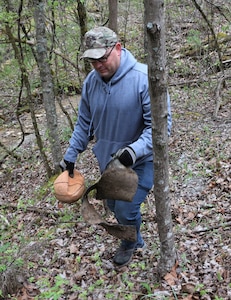 men and women gathering garbage and debris in the woods.