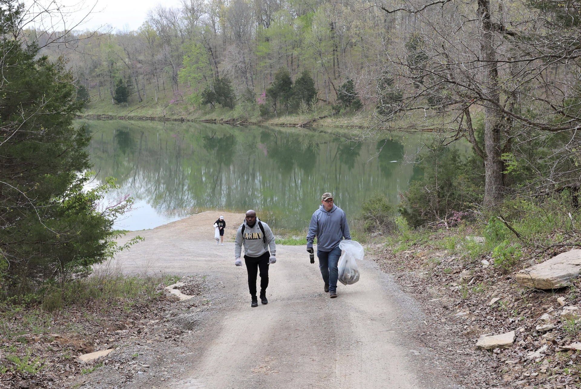 men and women gathering garbage and debris in the woods.