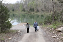 men and women gathering garbage and debris in the woods.