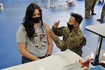 Sgt. Hien Nguyen, 730th Area Support Medical Company, South Dakota Army National Guard, vaccinates an Oglala Sioux Tribe member during a COVID-19 vaccination and health fair event in in Kyle, S.D., April 16, 2021. The 730th provided medical personnel to assist with administering COVID-19 vaccinations for members of the OST and to provide administrative support.
