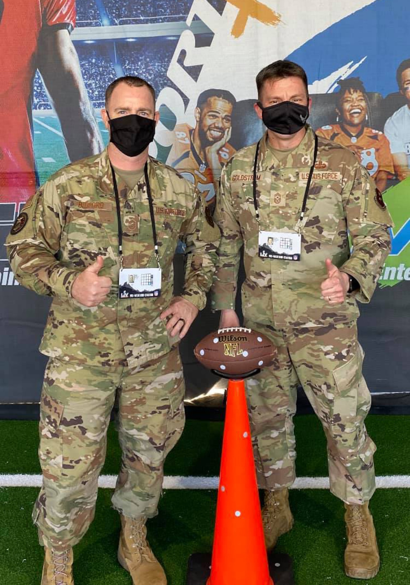 Master Sgt. Daniel Bedford, Air Force Recruiting Service national events program manager, and Chief Master Sgt. Antonio Goldstrom, AFRS command chief, pose for a photo at the AIR RAID QB SIM Experience during the Super Bowl LV Experience outside of Raymond James Stadium in Tampa, Florida, Jan. 31, 2021.